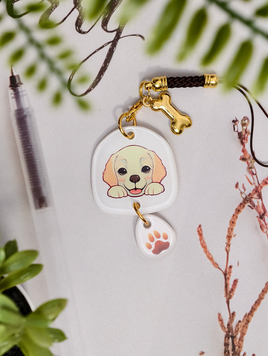 Labrador Retriever dog illustrated acrylic phone charm with a dangling paw print charm on a light surface with stationery.
